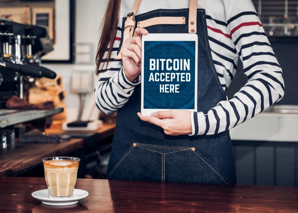 Close up woman barista holding tablet and show bitcoin accepted here on tablet screen at cafe counter bar,seller coffee shop accept payment by crypto currency.digital money concept.modern waitress