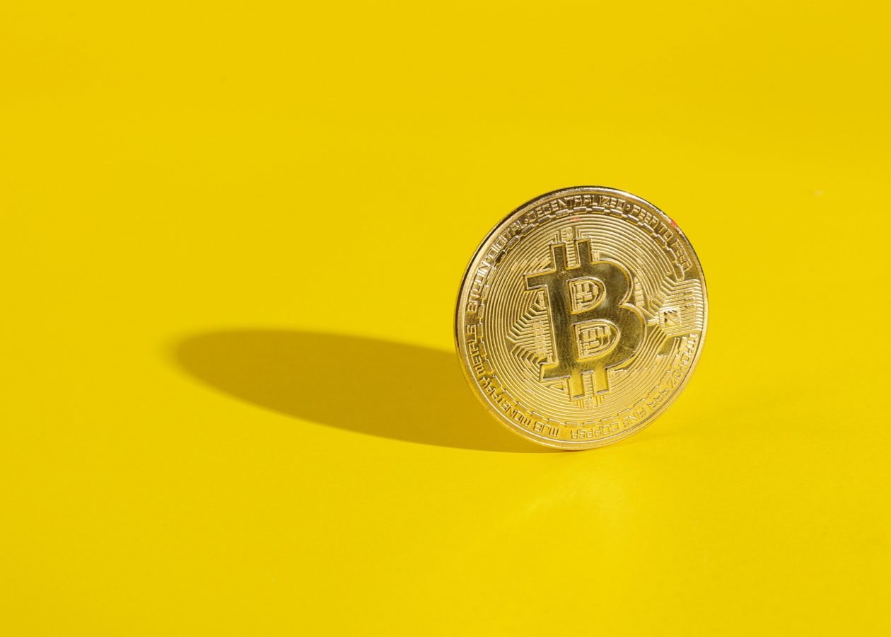 Gold bitcoin on a yellow background with a shadow. Cryptocurrency. Minimal financial layout